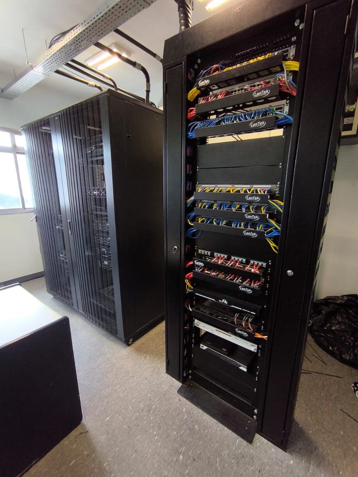 Sala de rack com armário aberto mostrando switches e patch panels